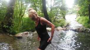 Alexa Cosmic trans girl swimming in font near waterfall wearing shorts and t-shirt...