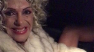 Shemale Prostitute Driving in Fur Coat, legs open, penis out
